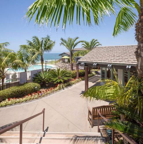 a walkway leading to a resort with a pool and palm trees at WCH at Wave Crest Resort in Del Mar