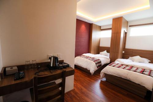 カトマンズにあるFlying Yak Kathmanduのベッド2台とデスクが備わるホテルルームです。