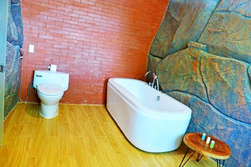 a bathroom with a bath tub and a toilet at Con Khuong Resort Can Tho in Can Tho