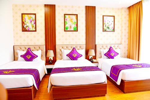 two beds in a hotel room with purple pillows at Con Khuong Resort Can Tho in Can Tho