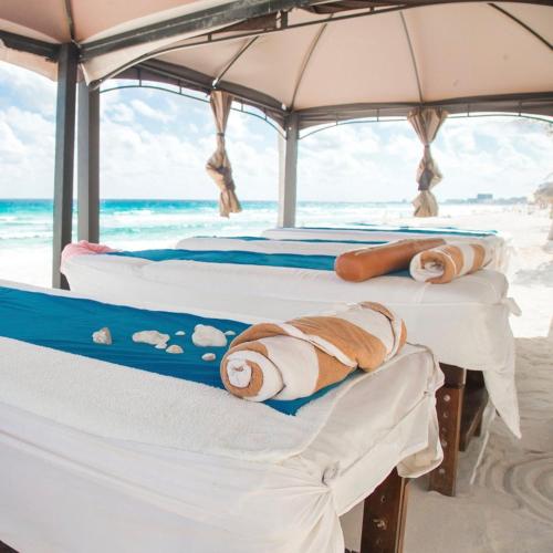a group of three beds on a beach at Condominio Girasol OceanView in Cancún