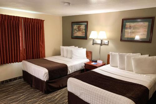a hotel room with two beds and a window at Rodeway Inn & Suites Sheridan in Sheridan