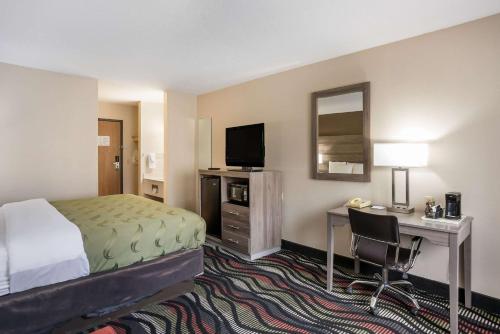 a hotel room with a bed and a desk with a computer at Quality Inn Cedar Rapids South in Cedar Rapids