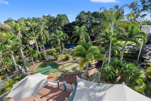 an aerial view of a golf course with palm trees at White Crest Apartments in Hervey Bay