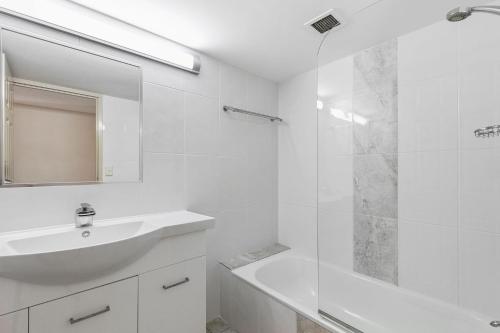 a white bathroom with a sink and a shower at White Crest Apartments in Hervey Bay