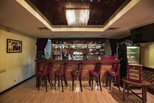 a bar with red bar stools and a bartender at Park Hotel Bishkek in Bishkek