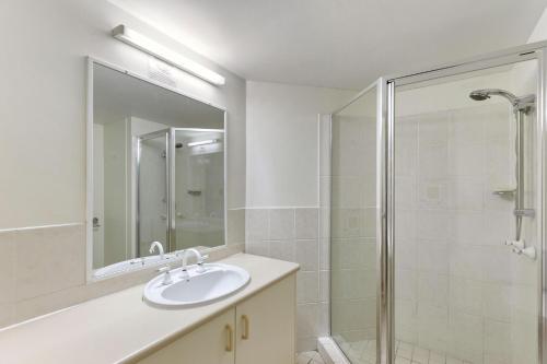 a white bathroom with a sink and a shower at White Crest Apartments in Hervey Bay