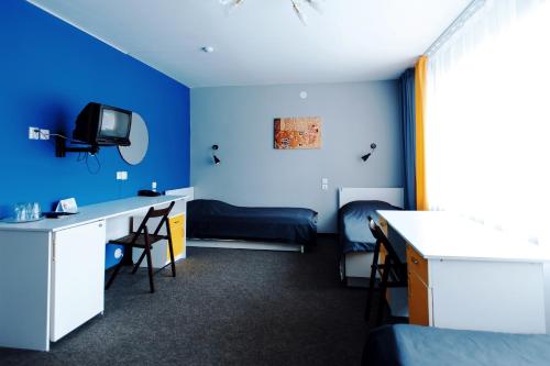a room with blue walls and a desk and a bed at Spasskaya Hotel in Vologda