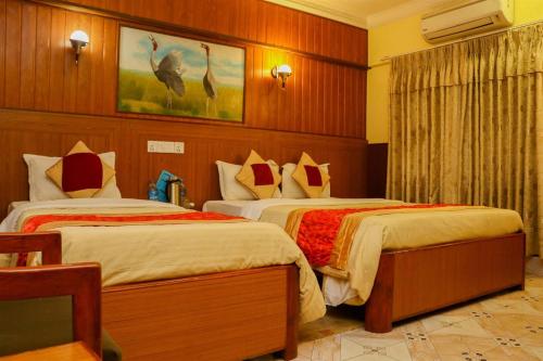 a hotel room with two beds with birds on the wall at Hotel Wildlife Camp in Sauraha