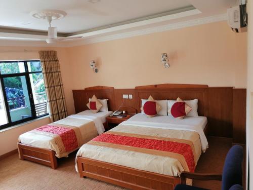 a hotel room with two beds and a window at Hotel Wildlife Camp in Sauraha