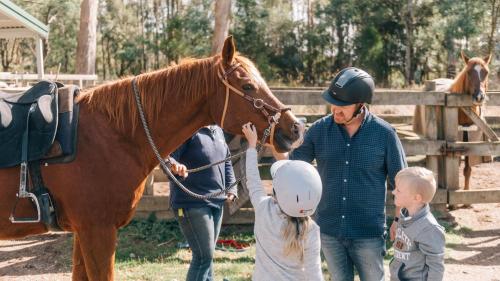 a man and a woman and a child petting a horse at Country Club Tasmania in Launceston