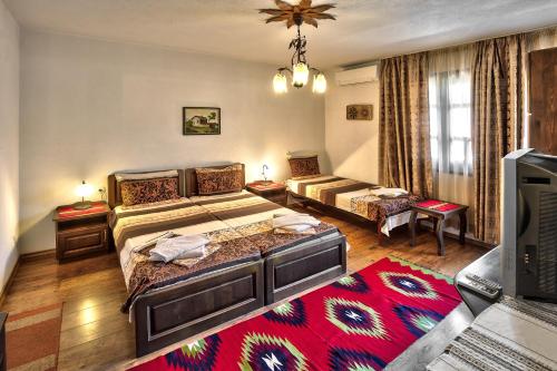 a bedroom with two beds and a living room at Keremidchieva Kushta Guest House in Sandanski