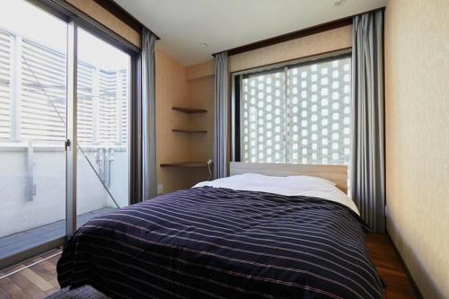 a bedroom with a bed and a large window at Kyodo Private House in Tokyo