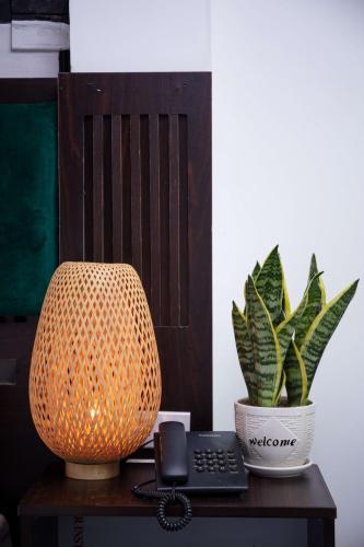 a desk with a lamp and a telephone and a potted plant at Hanoi Center Silk Lullaby Hotel and Travel in Hanoi