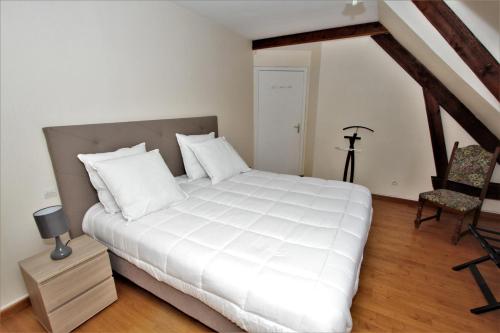 a bedroom with a large white bed and a chair at Hôtel Le Régent in Villers-Cotterêts