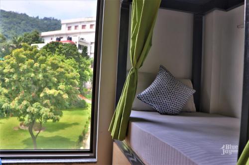 uma janela com vista para uma árvore em The Blue Jay Hostel - Dorms & Rooms em Rishikesh