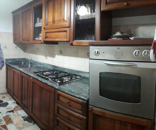 a kitchen with a stainless steel stove and wooden cabinets at Domuspes in Sedilo