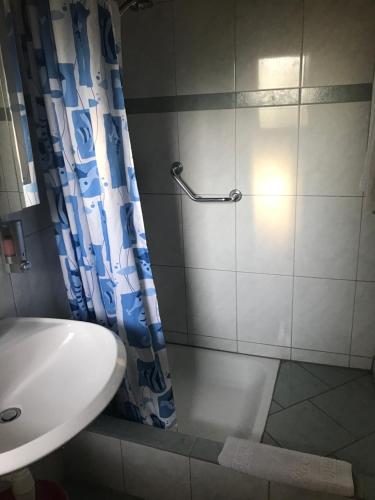 a shower with a blue shower curtain next to a sink at Motel City in Spreitenbach