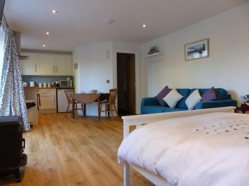 Littlemead - Newly renovated private studio near Glastonbury في غلاستونبري: غرفة نوم مع أريكة زرقاء ومطبخ