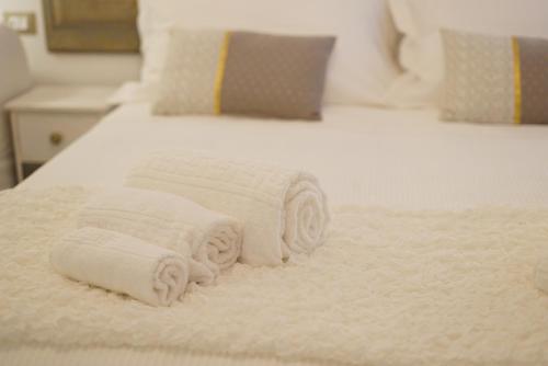 two towels are stacked on a white bed at Fermatiqui in Ravenna