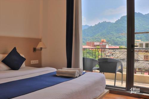 ein Hotelzimmer mit einem Bett und einem großen Fenster in der Unterkunft Blue Jay Hostel Rishikesh in Rishikesh