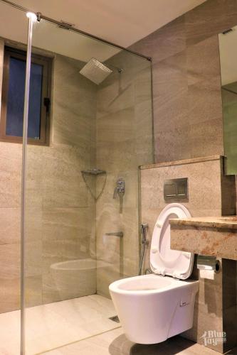 a bathroom with a toilet and a glass shower at The Blue Jay Hostel - Dorms & Rooms in Rishīkesh