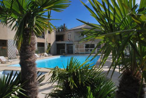 a swimming pool with palm trees in front of a house at Domaine Plein Sud in Bruzac