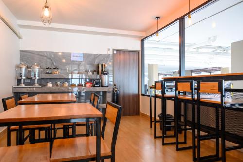 un restaurant avec des tables, des chaises et un comptoir dans l'établissement Donmueang Place Hotel - SHA Plus, à Bangkok