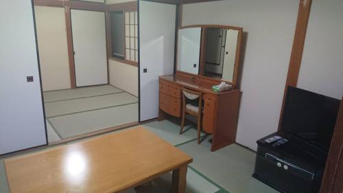 Zimmer mit einem Schreibtisch, einer Kommode und einem Spiegel in der Unterkunft Guesthouse Yoshikawa in Nara