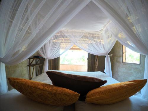 a white canopy bed with two pillows on it at Rumah Pampa at Pachamama in Nembrala