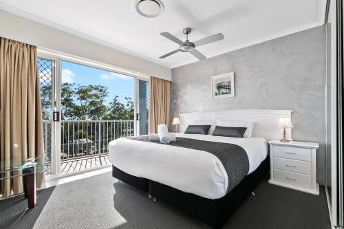 a bedroom with a large bed and a balcony at White Crest Apartments in Hervey Bay