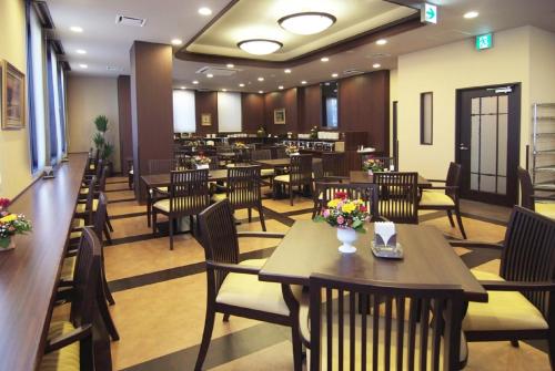 un comedor con mesas y sillas en un restaurante en Hotel Route-Inn Toki en Toki