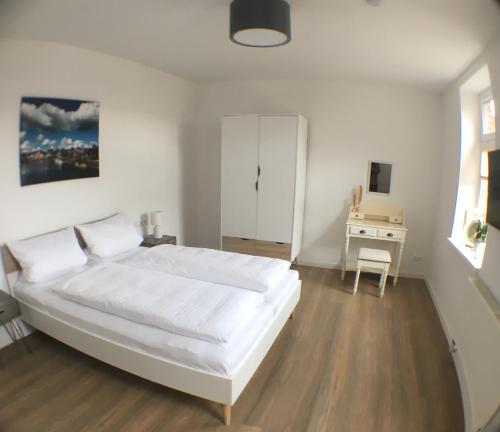 a bedroom with a large white bed and a desk at Das BilderbuchCafe - Ferien - Apartment NO 3 - Markt 7 in Havelberg