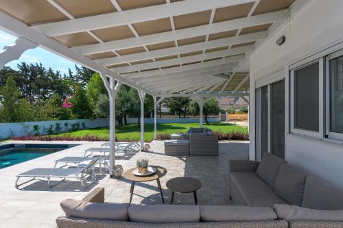 a patio with a couch and chairs under a pergola at Casa Bianca Villa in Kolymbia