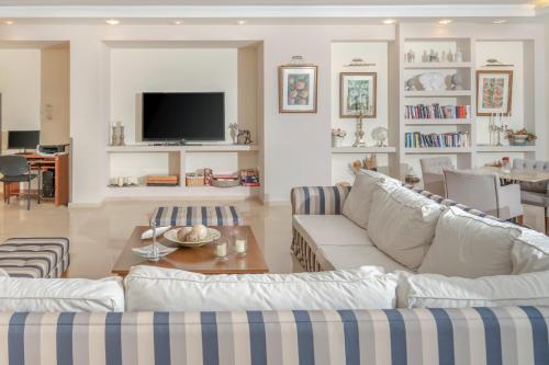 a living room with two white couches and a tv at Art Hotel Debono in Gouvia