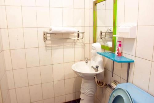 a bathroom with a sink and a mirror and a toilet at Comfort Hotel Entebbe in Lyamutundwe