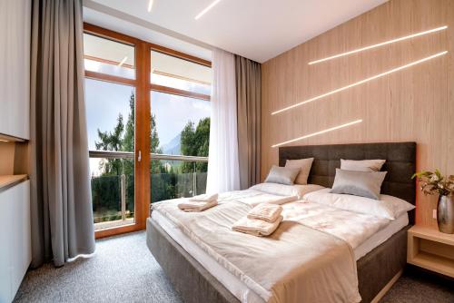 ein Schlafzimmer mit einem großen Bett und einem großen Fenster in der Unterkunft Apartment Luna Hrebienok C109 in Starý Smokovec