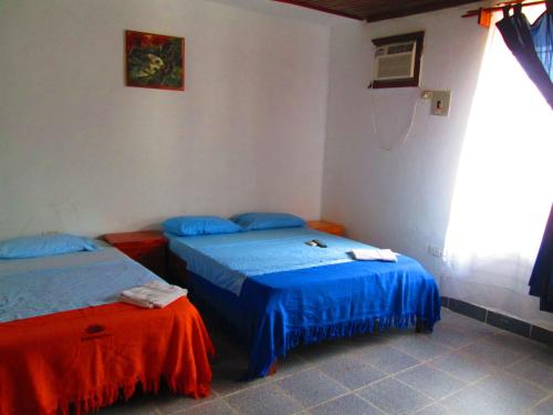 two beds in a room with blue and red sheets at Hotel Huito in Leticia