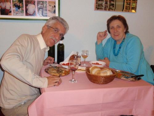an older man and woman sitting at a table with food at Saraj Guest House in Kulen Vakuf
