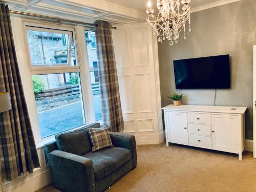 un salon avec une chaise et une télévision dans l'établissement Flat 2 Struan house, à Pitlochry