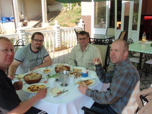 a group of men sitting around a table eating food at Saraj Guest House in Kulen Vakuf