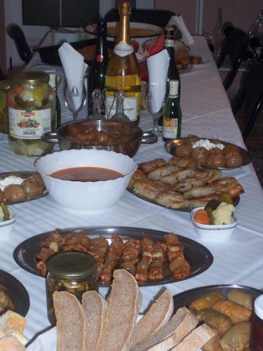 a table topped with plates of food and bottles of wine at Saraj Guest House in Kulen Vakuf