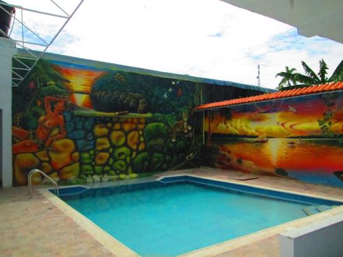 a swimming pool with a mural on the side of a building at Hotel Huito in Leticia
