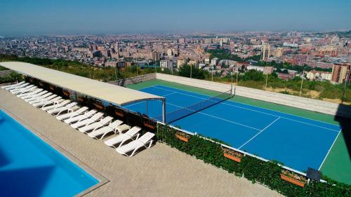 a tennis court with white lounge chairs and a tennis court at Panorama Resort&Suites in Yerevan