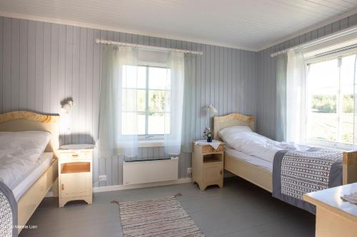 a bedroom with two beds and two windows at Kirkvollen pilegrimsgård in Tydal