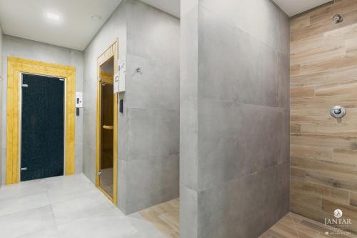 a walk in shower in a room with a wall at Jantar Apartamenty - DELUXE 38 Bałtycka 6 in Kołobrzeg