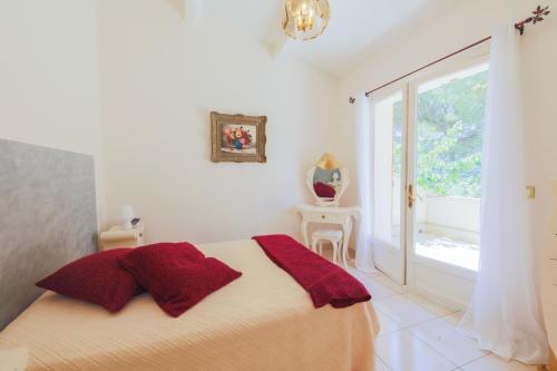 une chambre avec un lit avec des oreillers rouges et une fenêtre dans l'établissement LA ROHIERE - Tourrette-Levens, à Tourrette-Levens