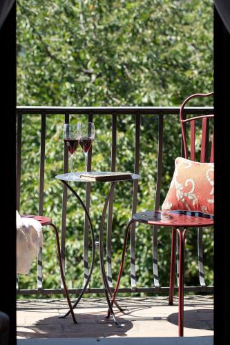 two glasses of wine sitting on a table on a balcony at Palazzo Malaspina B&B in Tavarnelle in Val di Pesa