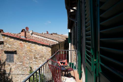 a red chair sitting on a balcony next to a building at Palazzo Malaspina B&B in Tavarnelle in Val di Pesa