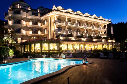 un hotel con piscina di fronte a un edificio di Hotel Villa e Palazzo Aminta a Stresa